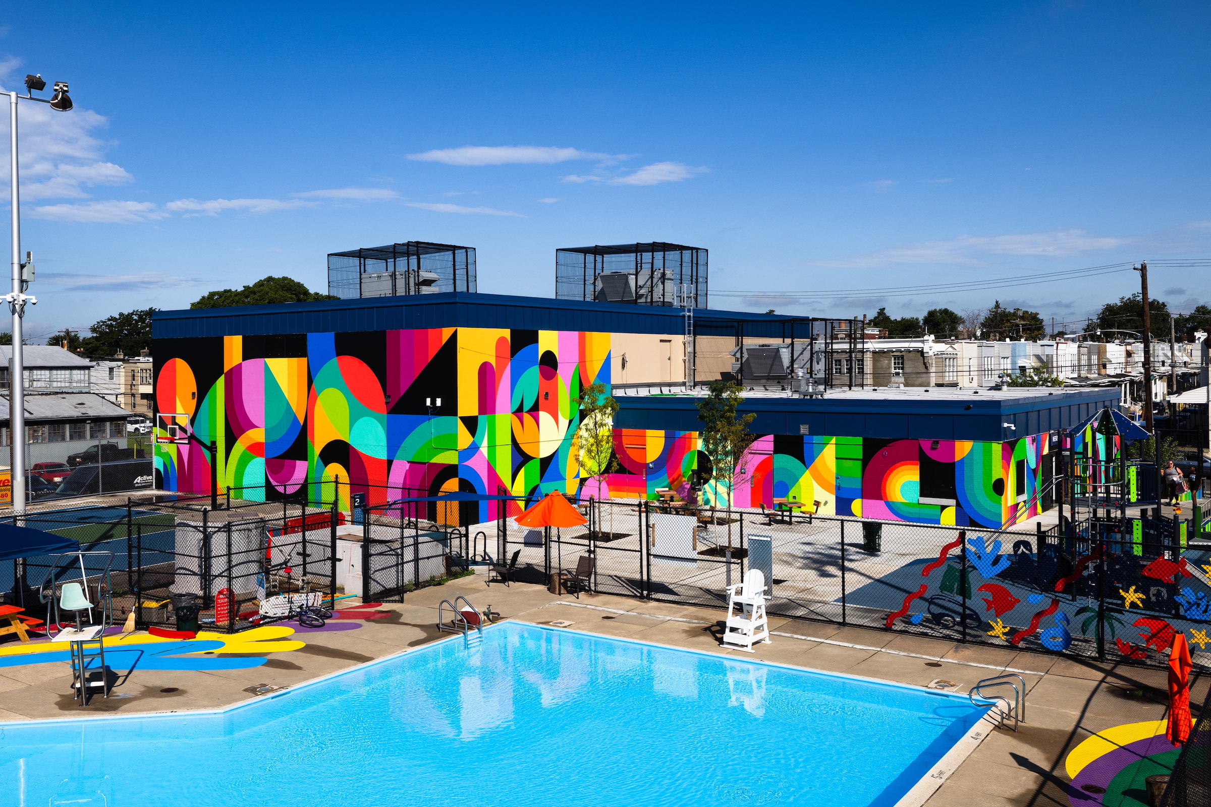 A recreation center with a colorful painted mural on the building outside by the pool.