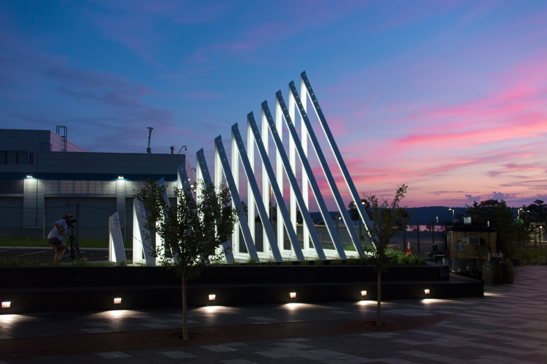 A large silver metal sculpture is placed outside, surrounded by trees and lights.