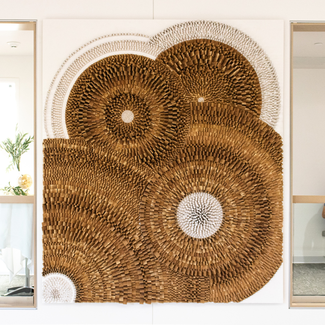 A large cedar wood sculpture hanging on a white wall.