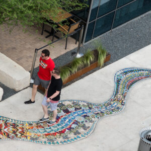 Aerial view of two people walking on a sidewalk with a colorful mosaic path