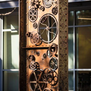 A tall sculpture featuring various interlocking gears and wheels.