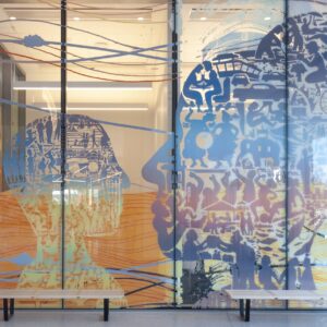 A mural on the glass wall depicts silhouettes of faces crafted from assorted objects