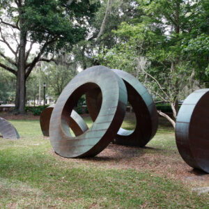 Sculpture in a park featuring five circular wooden forms with copper sheeting.